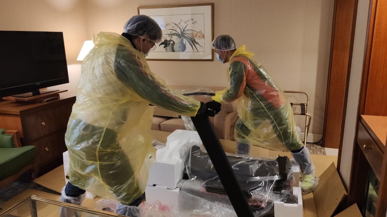 身著全套防護裝備的技師們在隔離客房內安裝跑步機