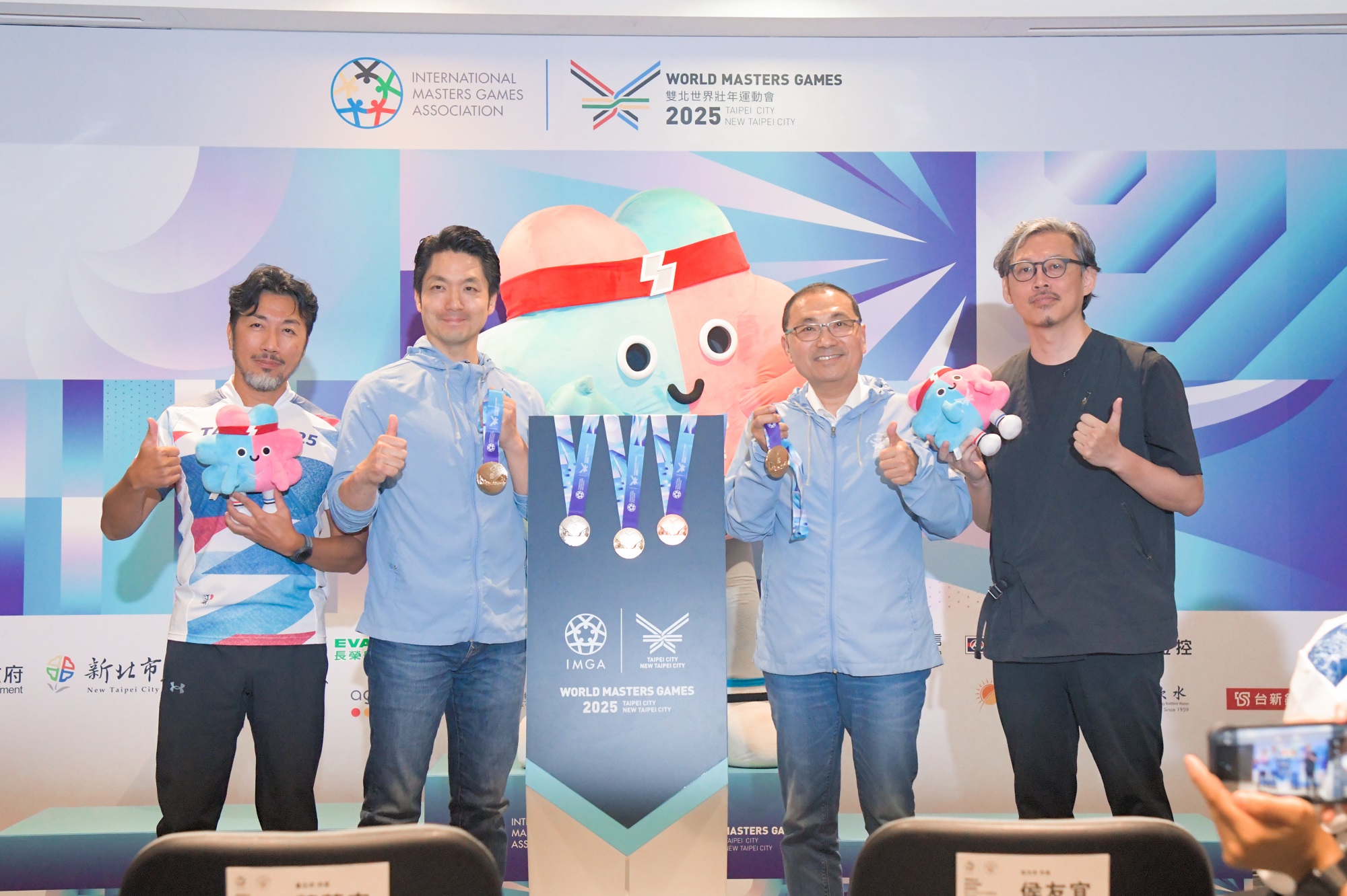 2025雙北世壯運主視覺系統暨獎牌設計公開發表會，雙北市長與獎牌設計總監江彥良(左一)、賽會主視覺專案計畫主持人張嘉倫(右一)合影