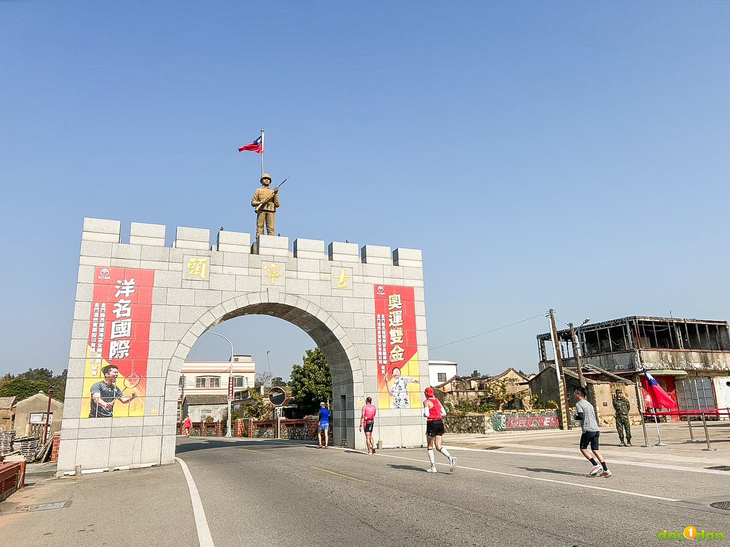 古寧頭牌樓，上方貼著拿下兩屆奧運羽球男子雙打金牌的金門籍選手李洋與她的金牌搭檔王齊麟